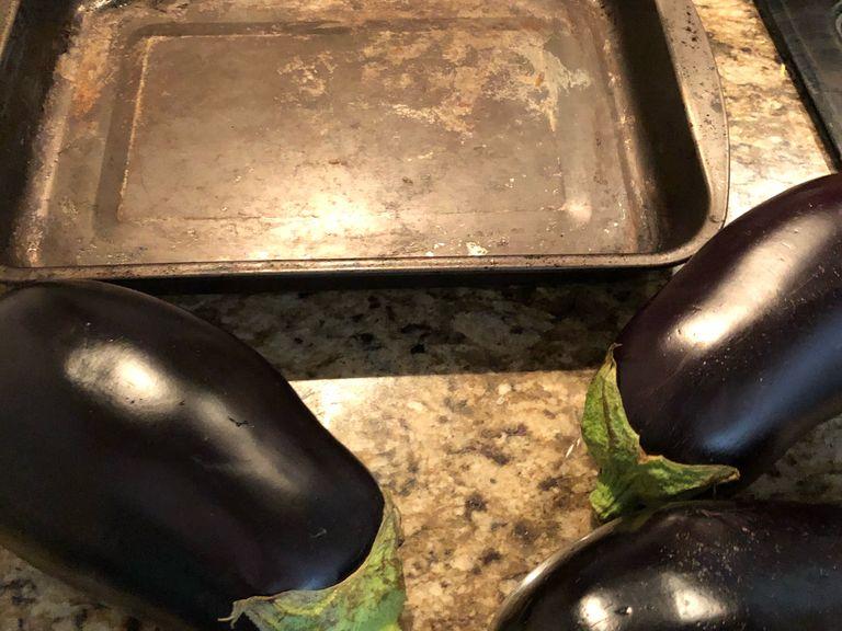 Wash the eggplant, dry it with paper towel and take some of the leaves off the eggplant. Once the leaves are removed, poke the whole eggplant with fork.