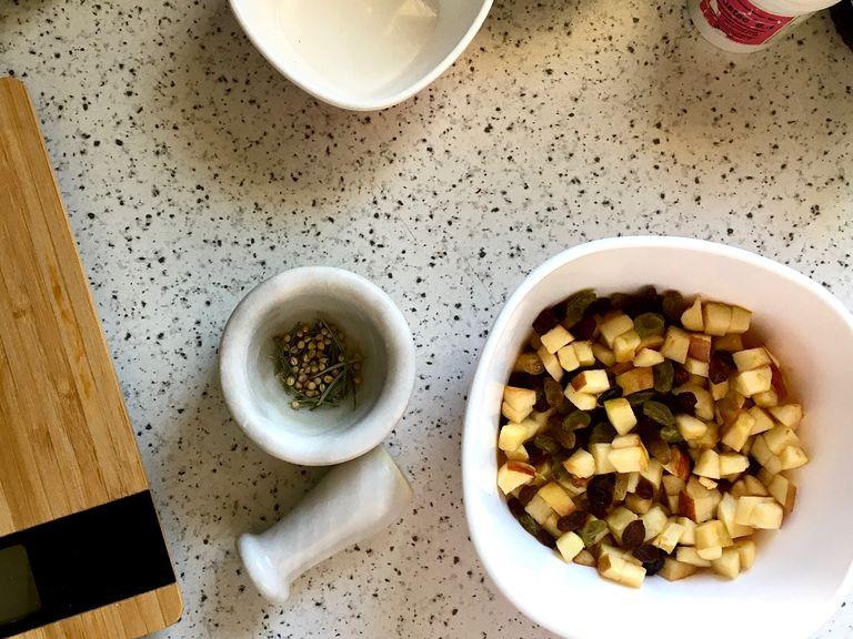 Dice the apples in a bowl. Squeeze half of a lemon over the apples to prevent them from browning. Add raisins and set aside. Preheat the oven to 190 C and prepare a muffin tin filling each cup with a muffin paper. Ground coriander seeds and rosemary if needed.