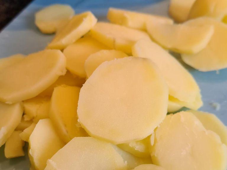 Kartoffeln abgießen und kurz abkühlen lassen. Die Kartoffeln dann noch warm in ca 0,5 cm dicke Scheiben schneiden.